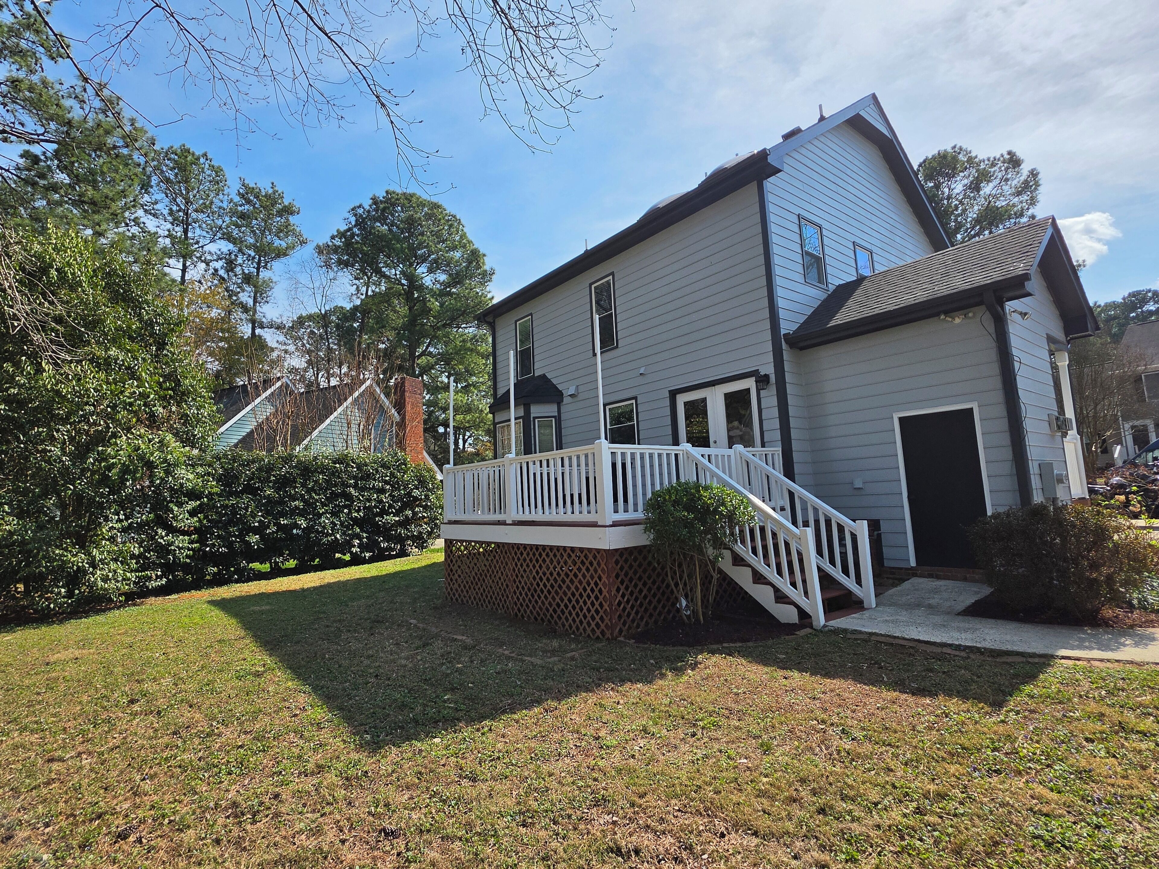 A two-story house with a white exterior, a front porch with a white railing, and a small deck.