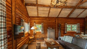 Ein Blockhaus-Interieur mit Holzboden, einem Ledersofa, einem Holztisch und einer Kristallleuchtre.