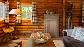 L’intérieur d’un chalet confortable, avec des murs en rondins de bois, une table en bois, une lampe, un jeu d’échecs et un canapé.