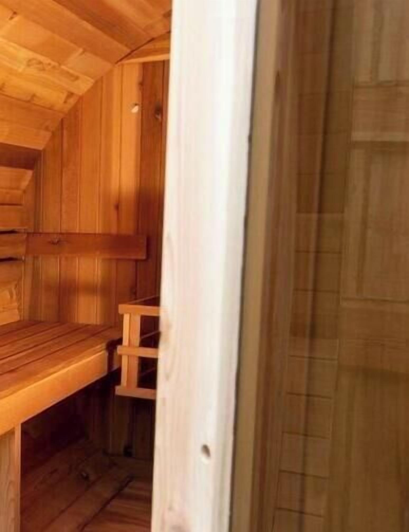 A wooden sauna room with benches and a wooden door.