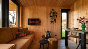 Et hyggeligt værelse med træpaneler, et Netflix-skilt, et lille bord med en vase og en bænk.