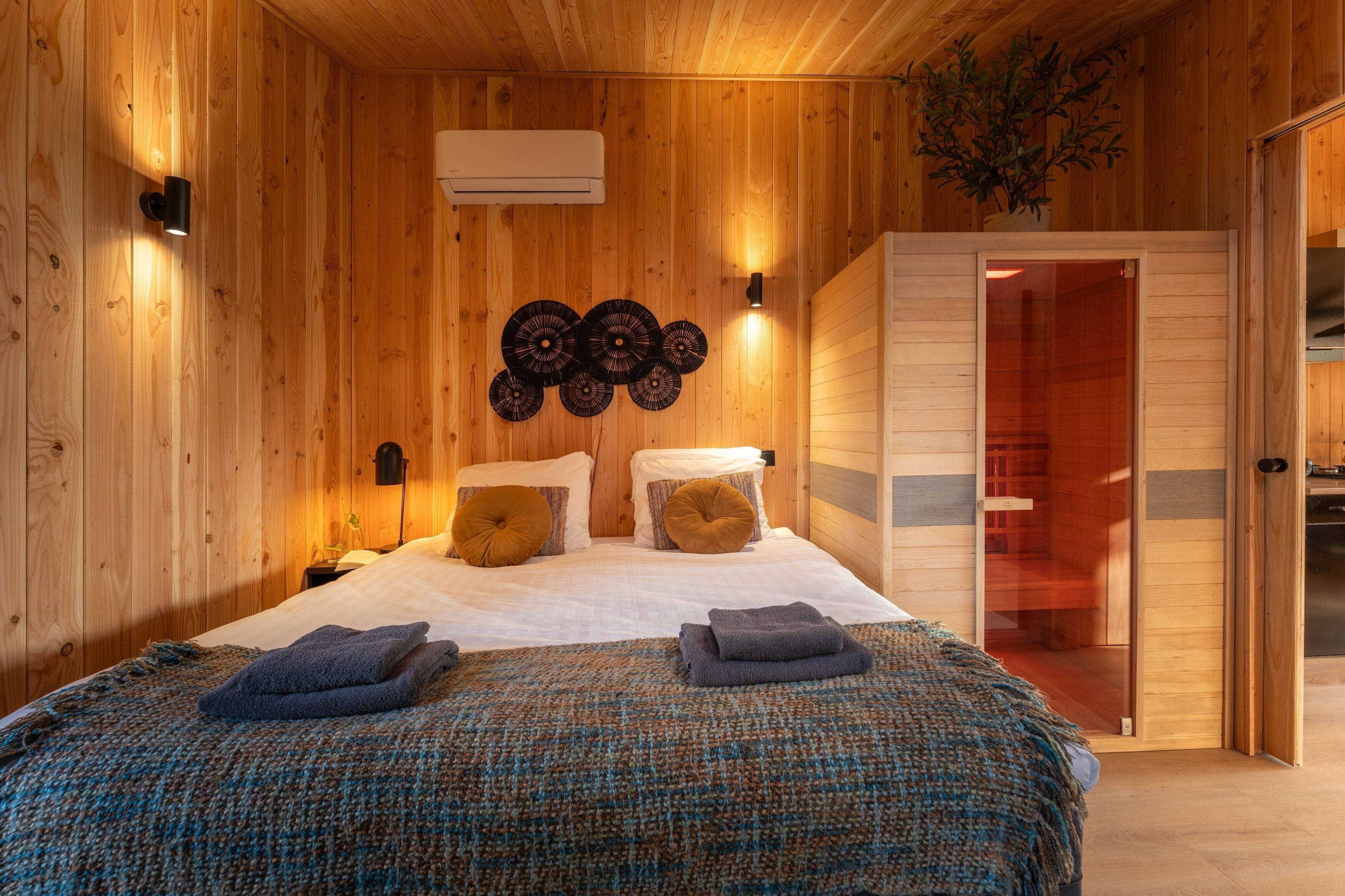 Ein Zimmer mit Holzvertäfelung, einem Bett, zwei Wandleuchten, einer Klimaanlage und einer Schiebetür zu einem anderen Raum.
