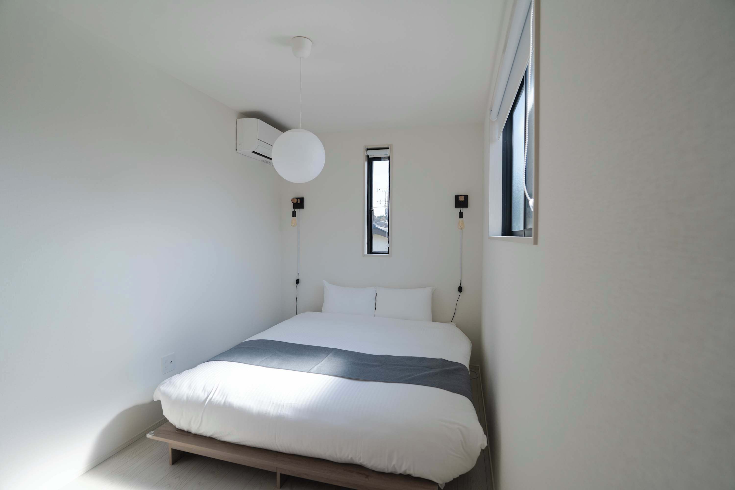 Een slaapkamer met een bed, een raam en een airconditioning.