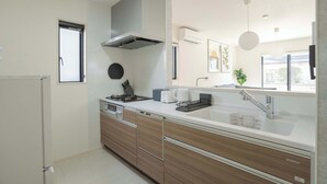A modern kitchen with a built-in stove, a range hood, and a large window.