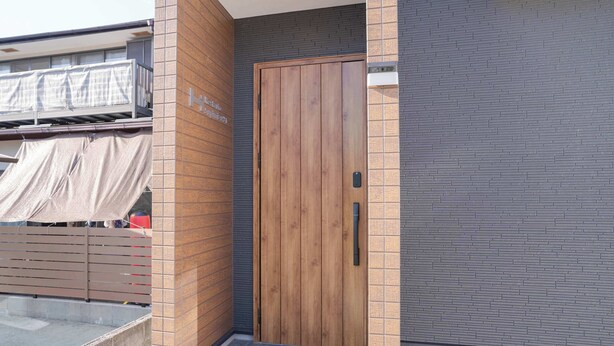 A wooden door with a handle, a brick wall, and a tiled floor.