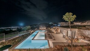 A nighttime view of a pool area with a rectangular pool, lounge chairs, and a stone wall. - Domaine–Sun,Luxury Eco Villa, private pool, great view (Chersonissos)