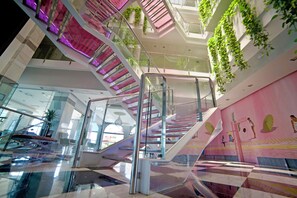 Et moderne interiør med en glasklædt trappe, metalgelændere og grønne planter på væggene.