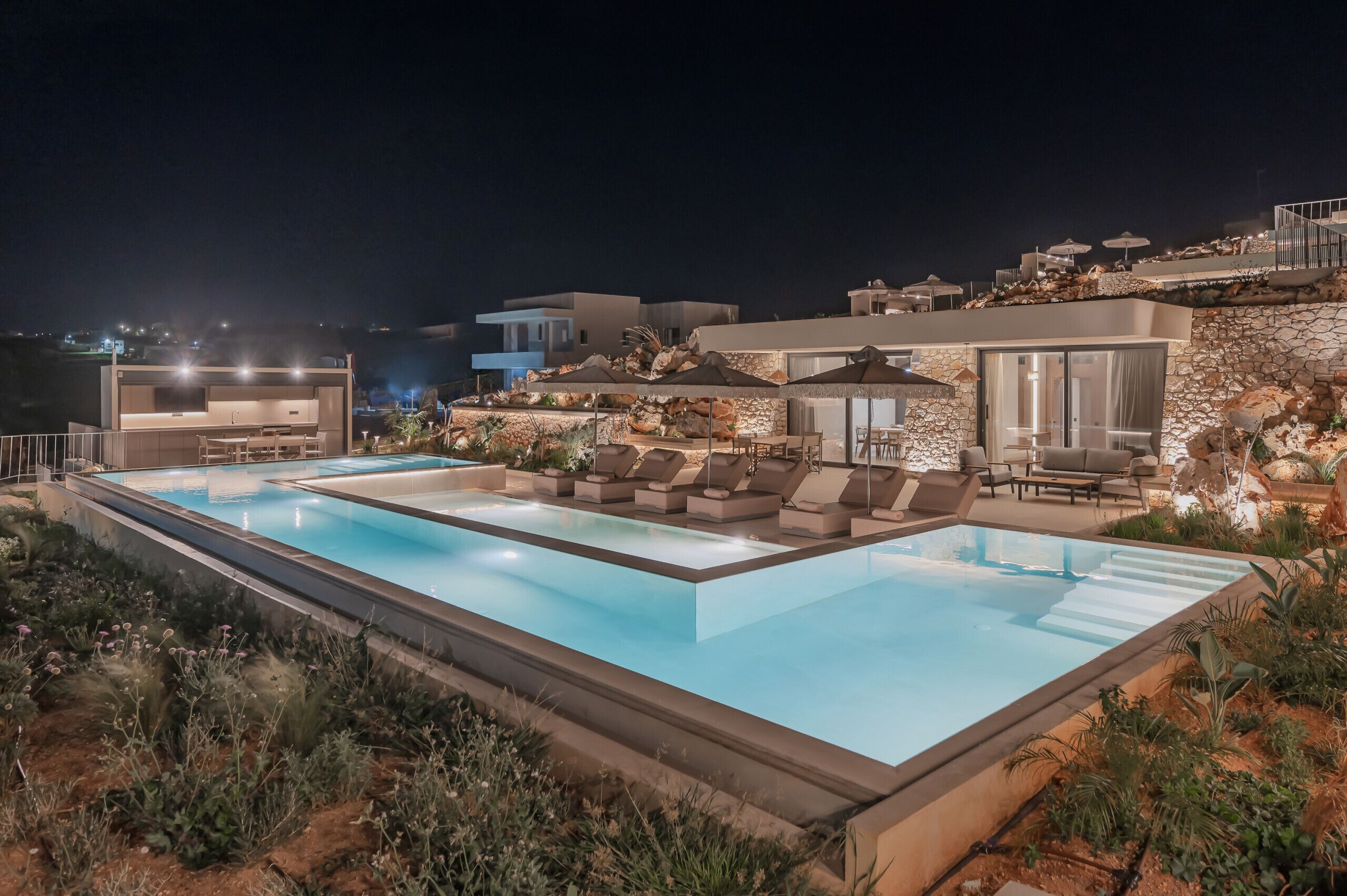 A large outdoor swimming pool with lounge areas and a stone wall.