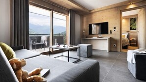 A modern hotel room with a balcony, a sofa, a small table, and a TV. - 5-room Duplex Apartment for 10 People, Prestige (Les Avanchers-Valmorel)