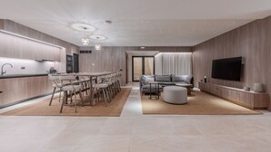 A modern kitchen with a dining area, a living room with a sofa and TV, and a staircase leading to another level. - Domaine Collection Earth Villa (Hersonissos)