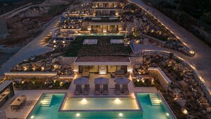A luxurious resort with multiple swimming pools, outdoor seating areas, and a well-lit landscape. - Domaine Collection Earth Villa (Hersonissos)