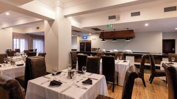 A restaurant with multiple tables, chairs, and a counter.