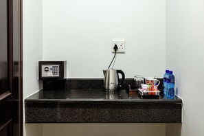 A kitchen counter with a coffee maker, a kettle, a water bottle, and a phone charging station. - Basden Wood Hotel Pty Ltd (Centurion)