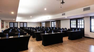A conference room with multiple tables, chairs, and water bottles.