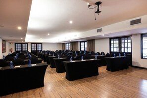 Un salón de conferencias con varias mesas, sillas y botellas de agua.
