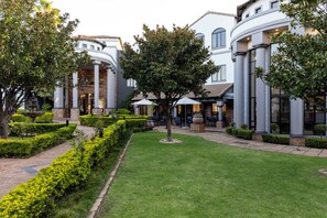 Un patio con una fuente, setos cuidados y zonas de estar al aire libre.