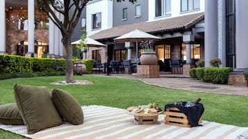 An outdoor seating area with a picnic setup, including a blanket, pillows, and food items.