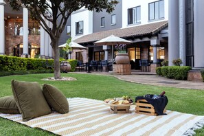 Un espacio al aire libre con un montaje para picnic, que incluye una manta, cojines y comida.