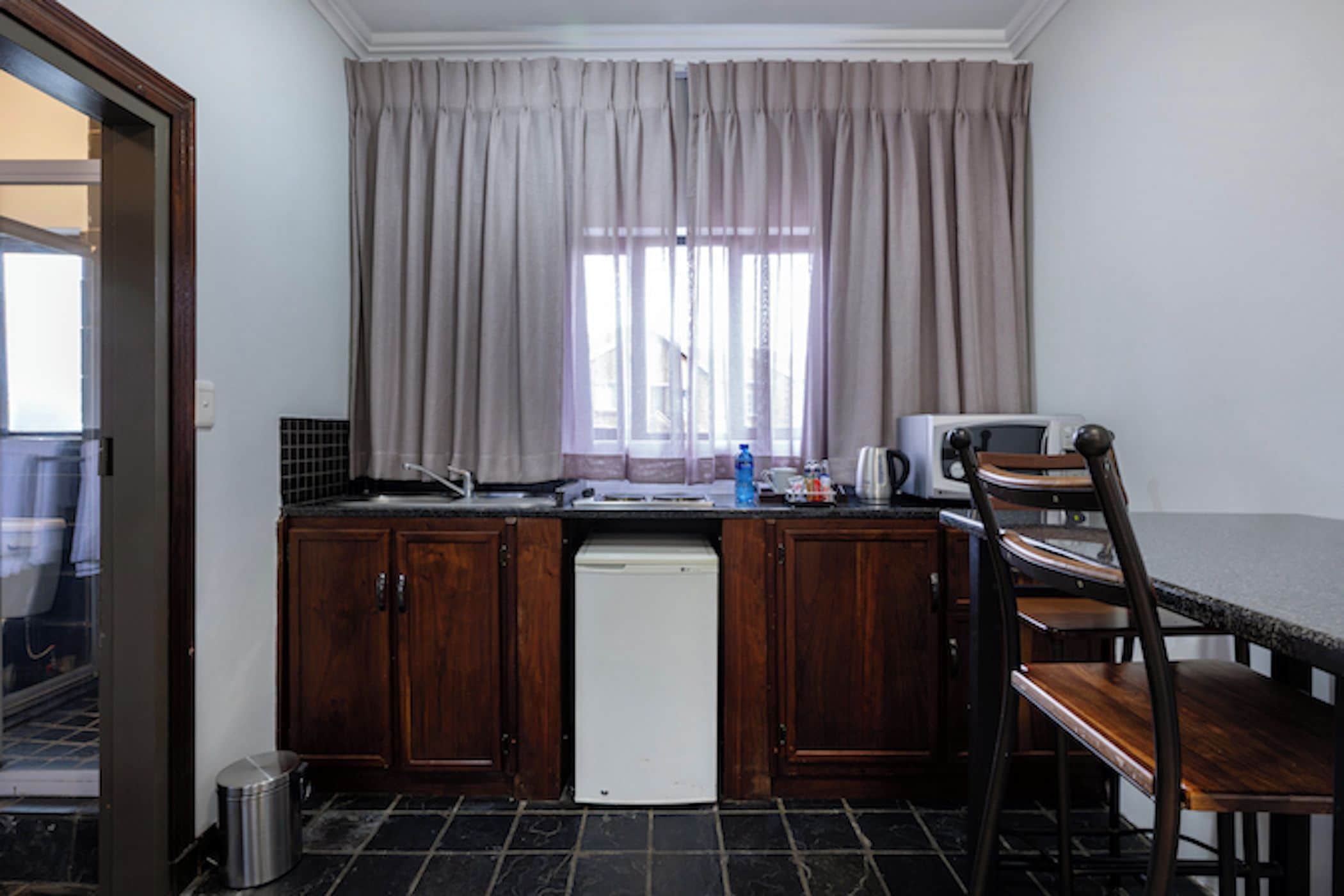Uma cozinha compacta com armários de madeira, uma máquina de lavar louça branca, um micro-ondas e uma área de refeições com uma mesa e cadeiras de madeira.