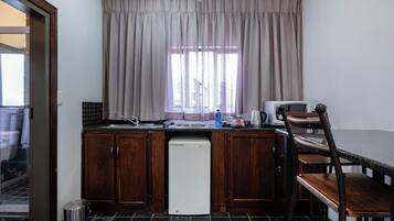 Uma cozinha compacta com armários de madeira, uma máquina de lavar louça branca, um micro-ondas e uma área de refeições com uma mesa e cadeiras de madeira.