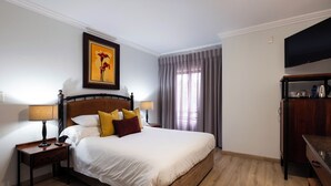 Una habitación de hotel con una cama, mesitas de noche, un televisor y un cuadro en la pared.