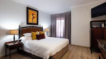 Quarto de hotel com uma cama, mesas de cabeceira, uma televisão e um quadro na parede.