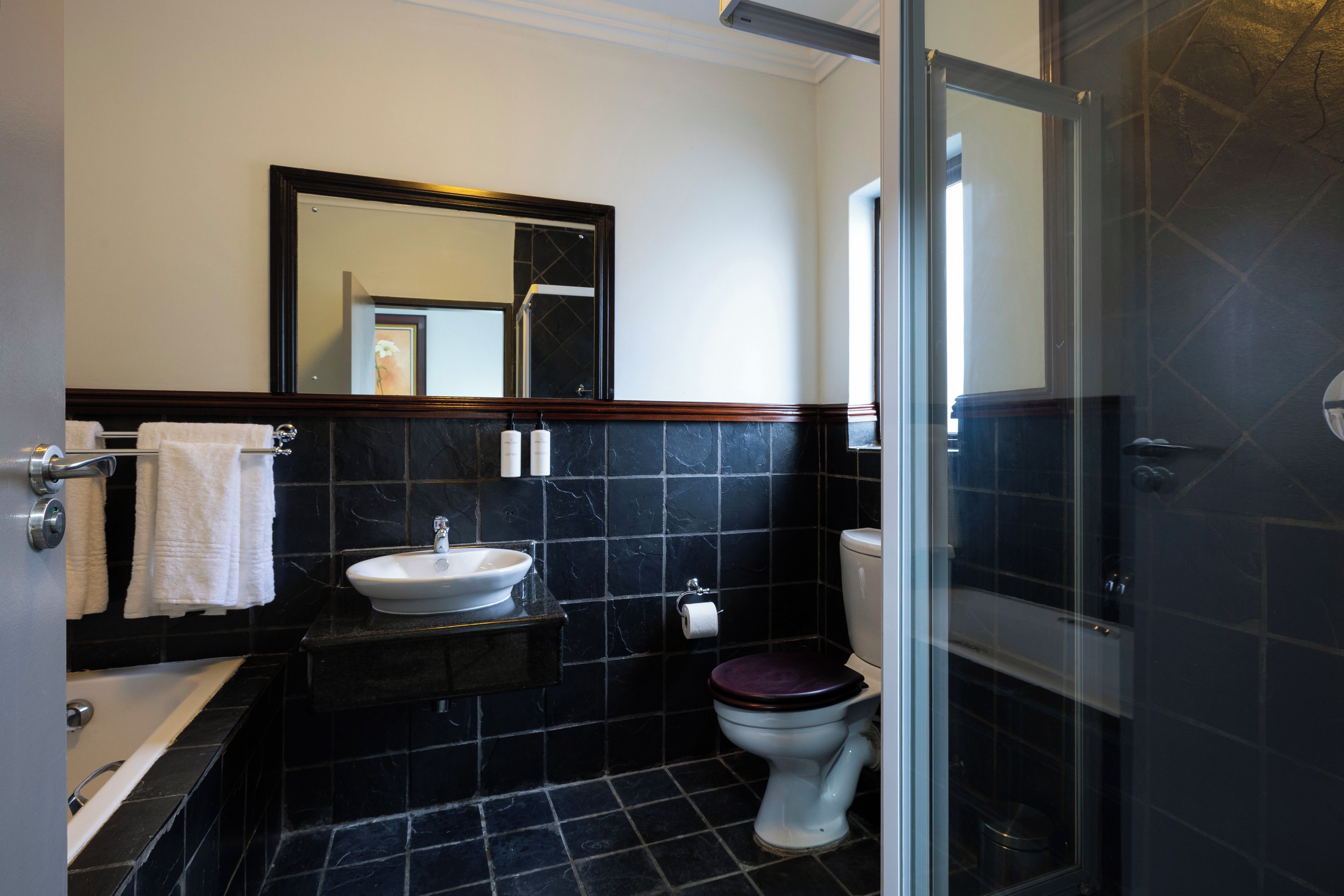 Un baño con bañera, lavamanos, inodoro y espejo.