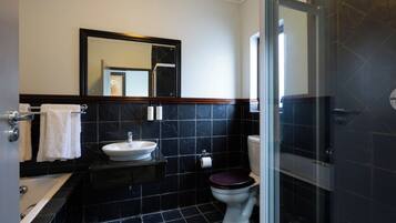 Un baño con bañera, lavamanos, inodoro y espejo.