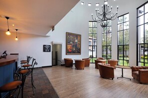 Un vestíbulo amplio con zona de bar, asientos y ventanas grandes.