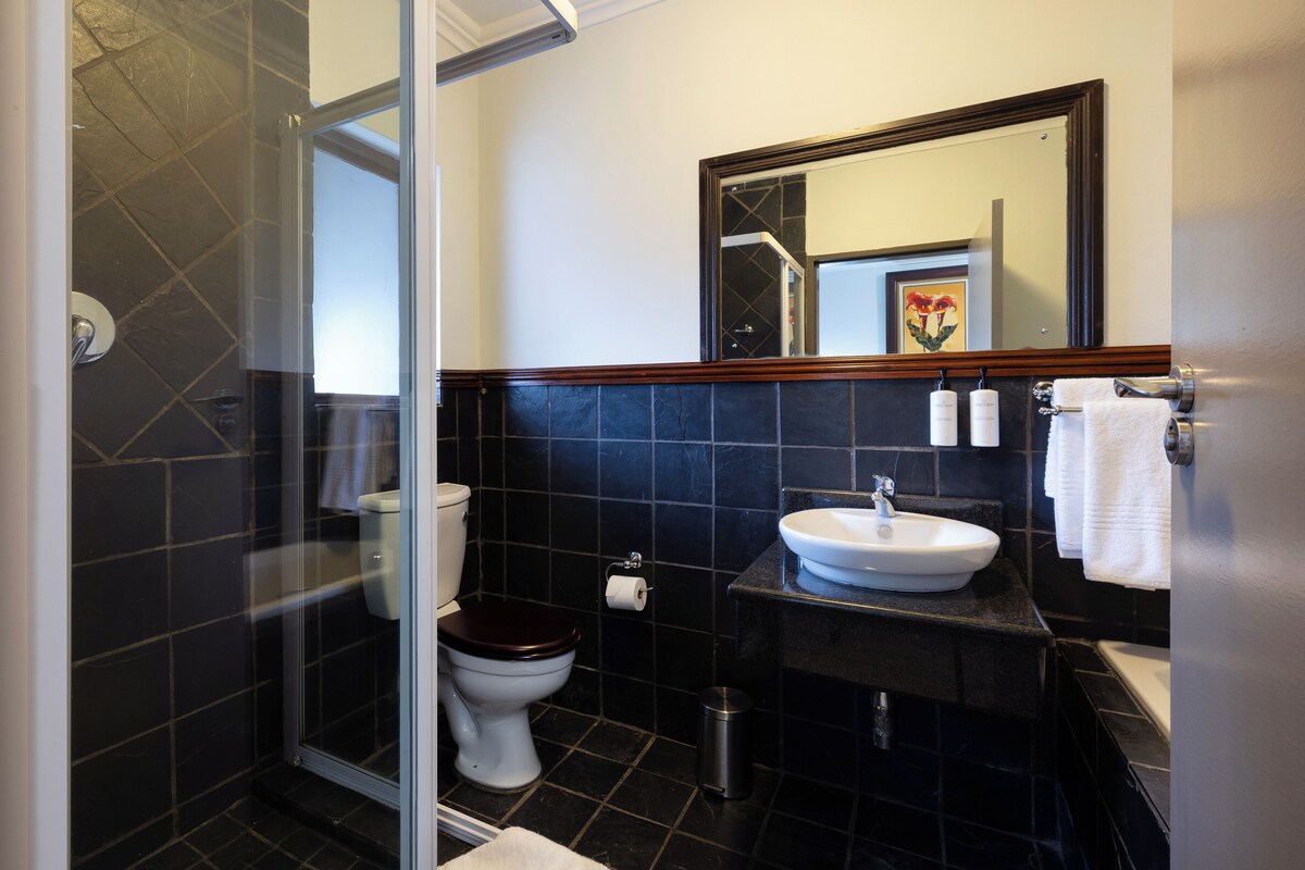 Un baño con cabina de ducha de vidrio, inodoro, lavabo y espejo.