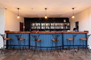 Un bar con mostrador de madera, taburetes de metal negro y pared azul.