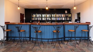 A bar with a wooden counter, black metal stools, and a blue wall.