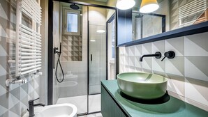 Ein modernes Badezimmer mit einem grünen Waschbecken, einem Bidet und einer Duschkabine aus Glas.