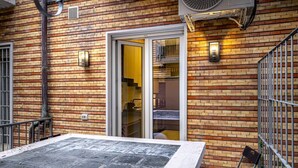 Eine Fassade aus Ziegelsteinen, eine Schiebetür, ein Metallgeländer und ein Tisch mit einem Stuhl.