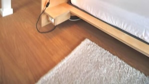 Un dormitorio moderno con cama, mesita de noche, lámpara y un espejo grande.