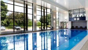 En swimmingpool med glasvægge, stole og udsigt ud