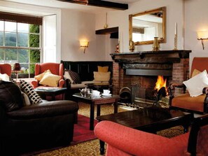 Un salón acogedor con chimenea, sofás de cuero y vistas al exterior.