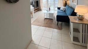 A modern living room with a sofa, coffee table, and TV. - Amselkoje - Holiday apartment "Amselkoje" in Westerland is a real feel-good place (Sylt)