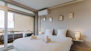 Une chambre d’hôtel moderne dotée d’un grand lit, d’un balcon avec vue et d’un climatiseur fixé au mur.
