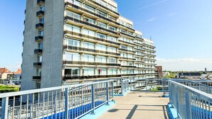 Un immeuble à plusieurs étages doté de balcons, d’un pont piétonnier et surplombant un ciel dégagé.