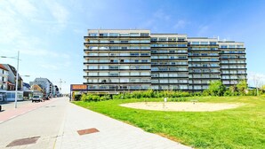 Un immeuble à plusieurs étages doté d’une architecture moderne, caractérisé par une série de balcons et de grandes fenêtres.