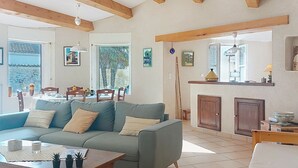 A living room with a sofa, coffee table, and dining area with chairs and a table. - Le Château 3 by Interhome (Ile d'Oléron)
