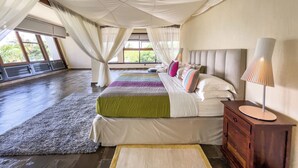 A spacious bedroom with a large bed, a nightstand, and a window with curtains. - Cocokinondo Villa & Boutique Hotel (Diani Beach)