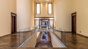 A spacious interior with a glass railing, a central staircase, and a view of a staircase leading to another level. - Cocokinondo Villa & Boutique Hotel (Diani Beach)