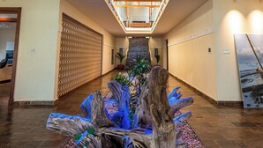 A spacious hallway with a central decorative wooden structure, a staircase, and a view of the upper floor. - Cocokinondo Villa & Boutique Hotel (Diani Beach)