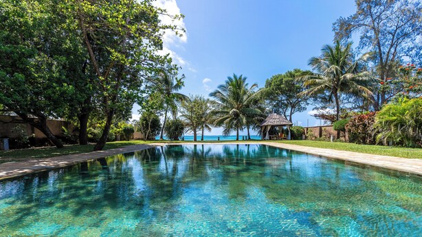 A clear swimming pool surrounded by tropical vegetation and a gazebo. - Cocokinondo Villa & Boutique Hotel (Diani Beach)