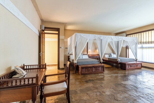 A room with a wooden bed, a wooden desk, a telephone, and a window with curtains. - Cocokinondo Villa & Boutique Hotel (Diani Beach)