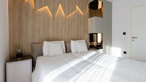 A modern bedroom with a large bed, a nightstand, a mirror, and a wooden accent wall.