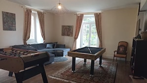 A living room with a pool table, sofa, and foosball table. - Élégance Périgourdine (Beaumontois en Périgord)
