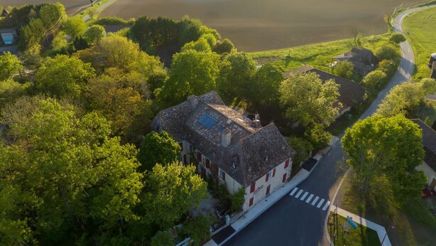 An aerial view of a rural area with a small building surrounded by lush greenery and a winding road. - Élégance Périgourdine (Beaumontois en Périgord)